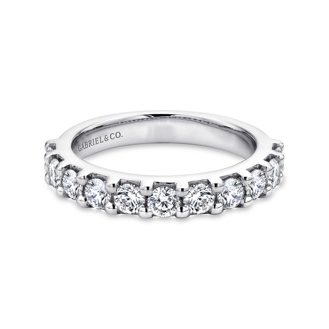 A white gold ring lies flat against a white background. The band features eleven brilliant-cut diamonds in a straight line.