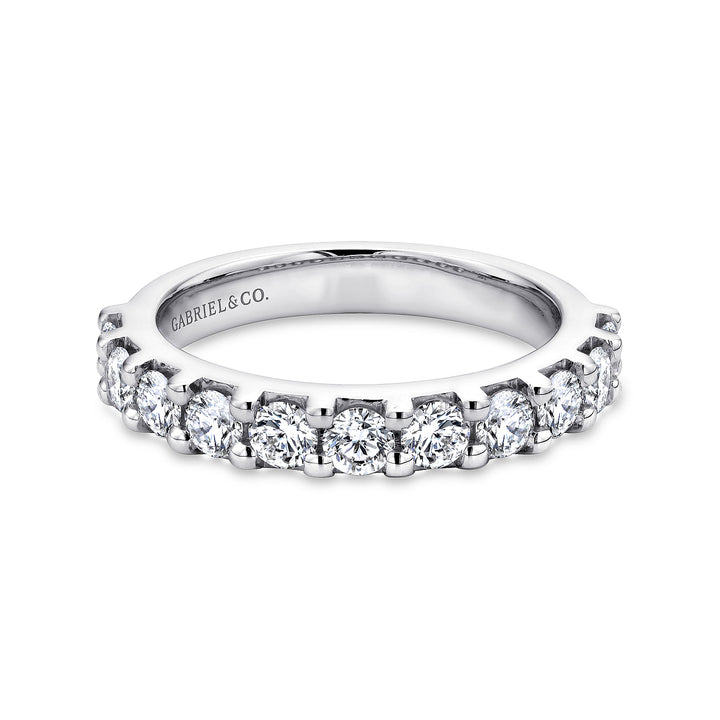 A white gold ring lies flat against a white background. The band features eleven brilliant-cut diamonds in a straight line.