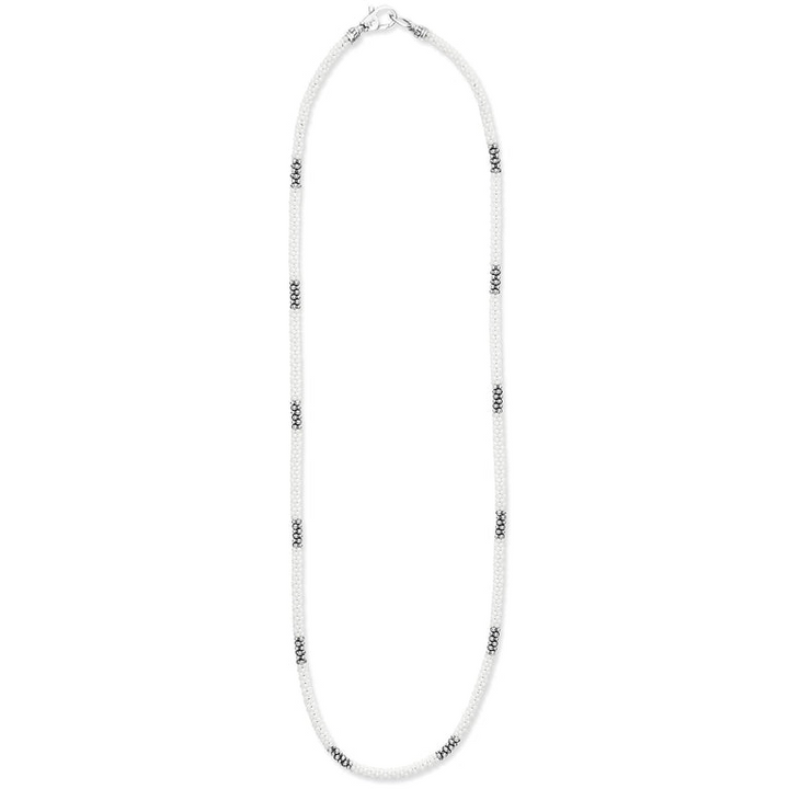 A sterling silver and ceramic beaded necklace in the middle of a white background featuring white ceramic and silver Caviar beading.