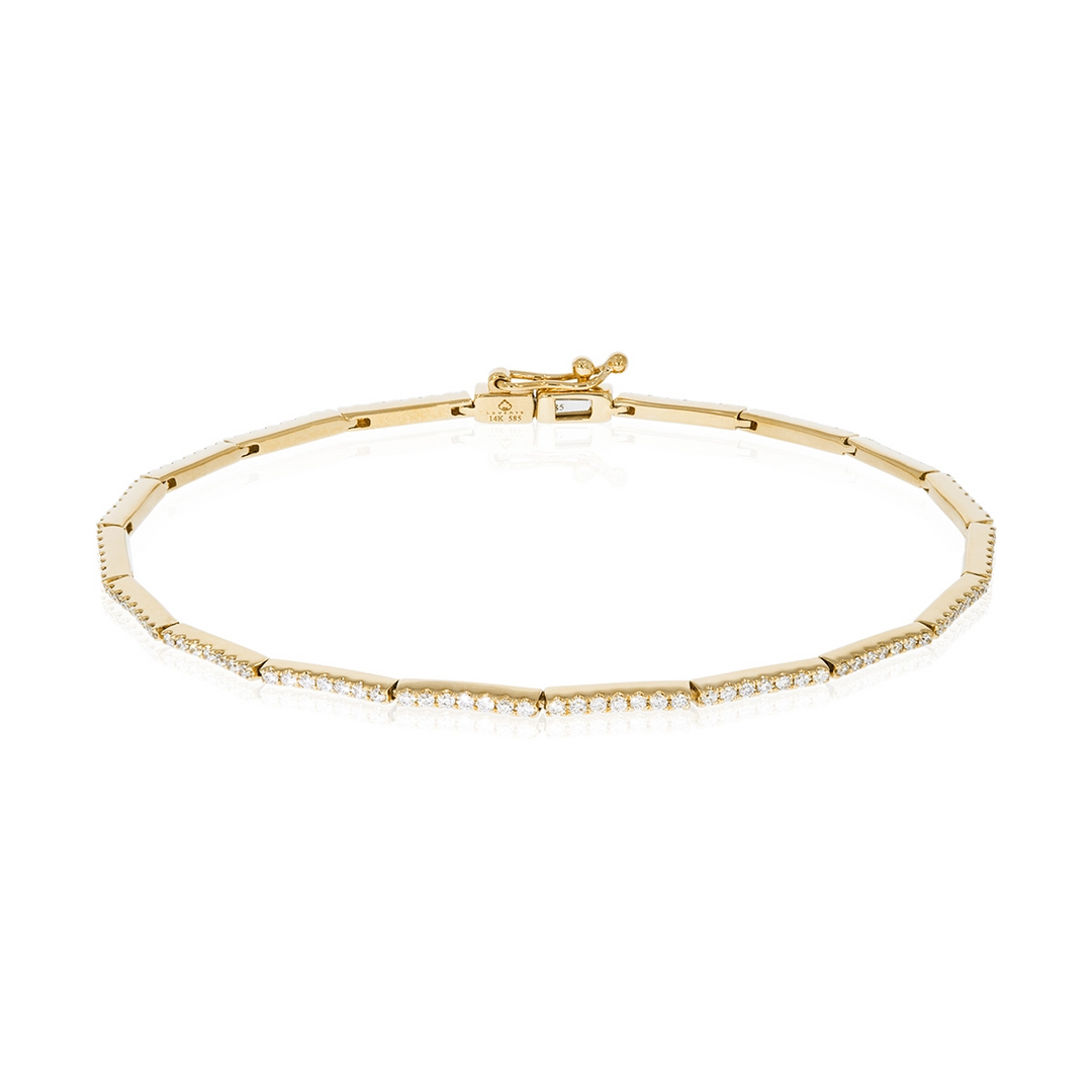 A yellow-gold bracelet lies flat on a white background. It features sleek bars of pave-set diamonds.