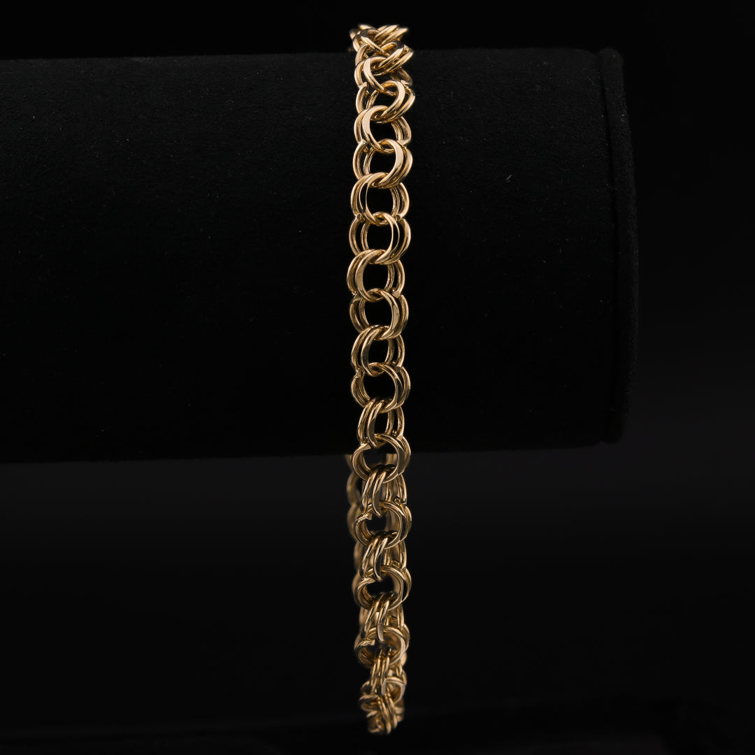 A close-up of a yellow-gold chain featuring interlocking double links against a black background.