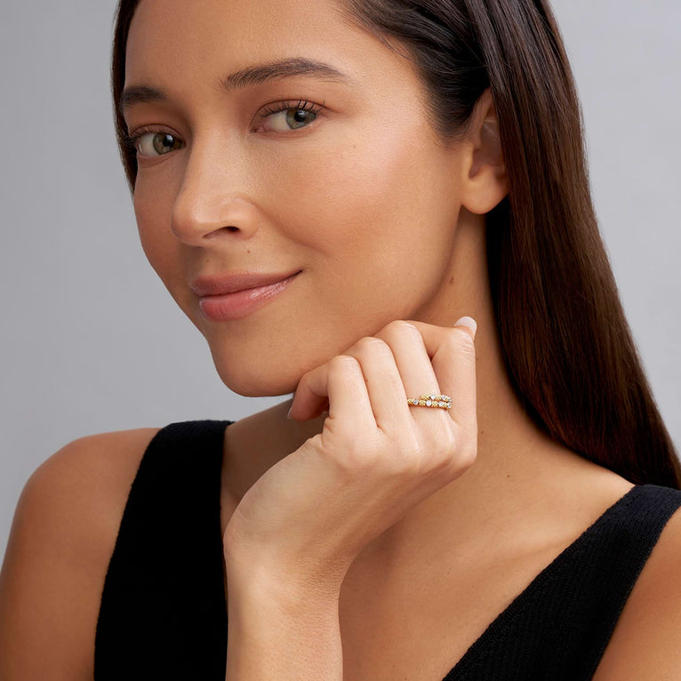 A woman wearing An 18K Gold ring in the middle of a white background featuring diamonds surrounded by 18k gold superfine Caviar beading in a wrap design.