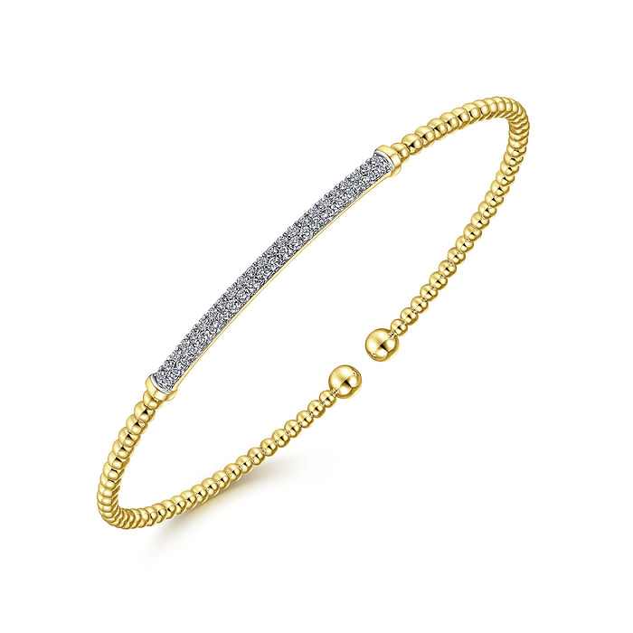 A yellow-gold bangle bracelet with a beaded band, two rows of diamonds in the middle, and end caps is angled in the middle of a white background.