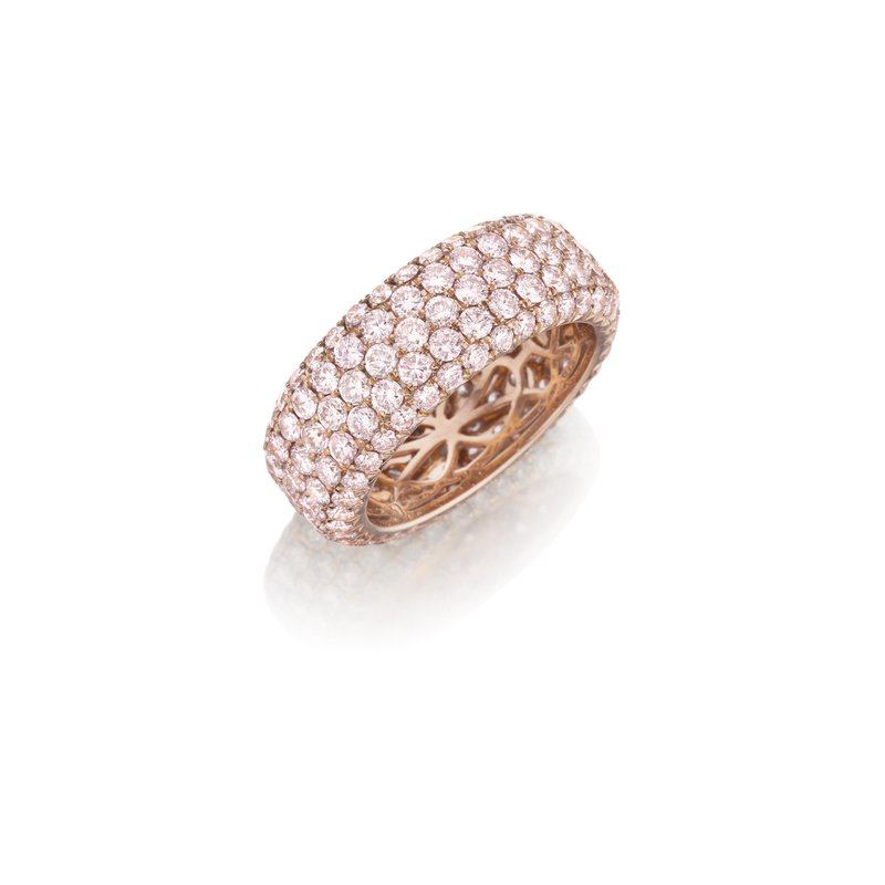 A rose-gold ring lies flat against a white background. It features a pave diamond-set wide band. 