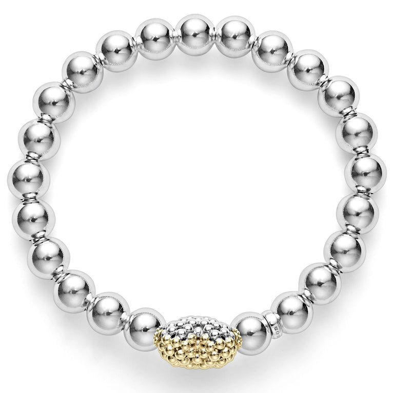 An overshot view of a sterling silver and 18k gold beaded bracelet in the middle of a white background featuring an 18k gold and silver Caviar beaded heart accent