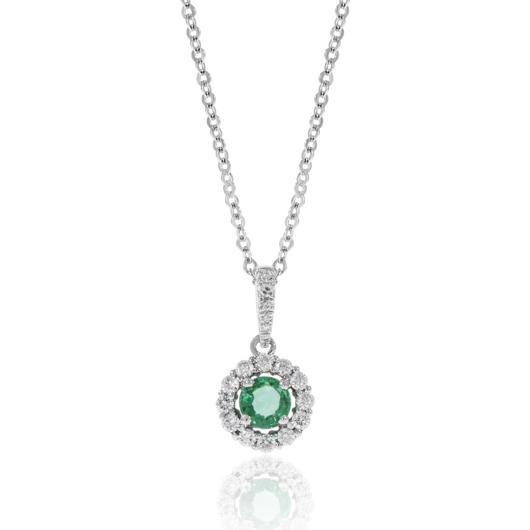 A close-up of a white-gold Halo Necklace against a white background. The necklace features an emerald round-cut center stone surrounded by round diamonds. 