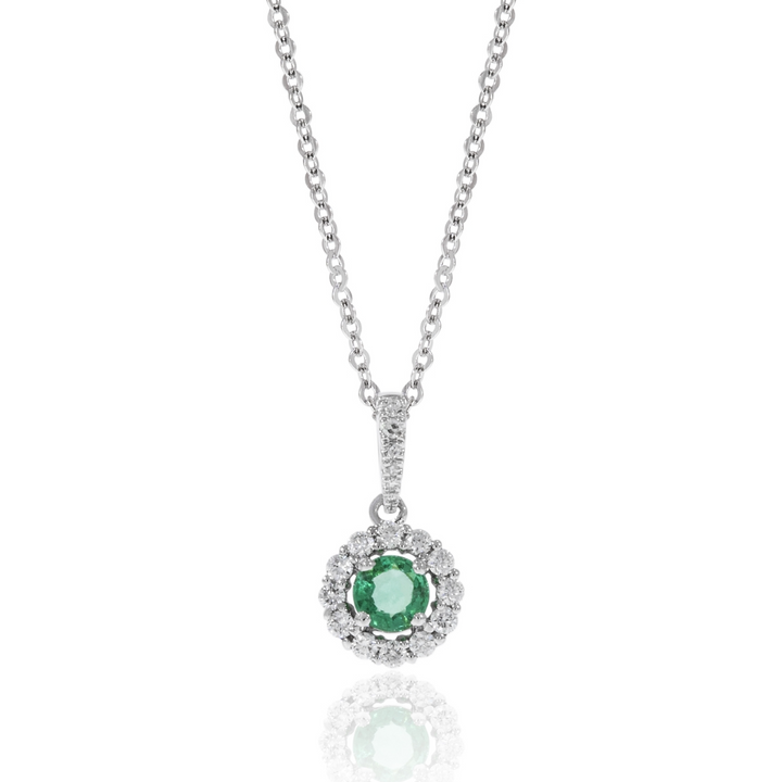 A close-up of a white-gold Halo Necklace against a white background. The necklace features an emerald round-cut center stone surrounded by round diamonds. 