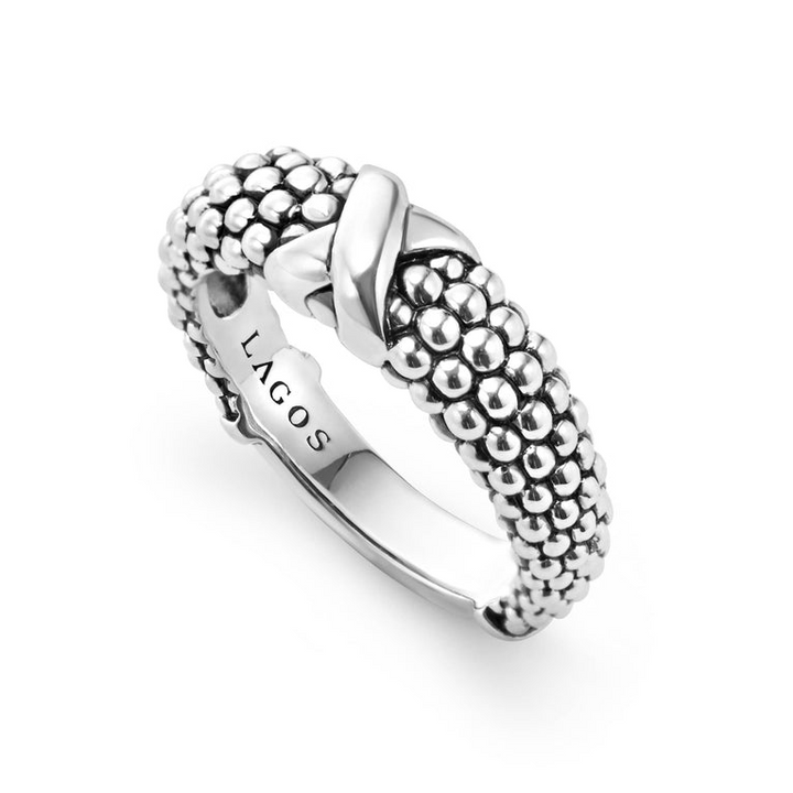 A sterling silver ring displayed angled in the middle of a white background featuring an x motif and silver Caviar beading