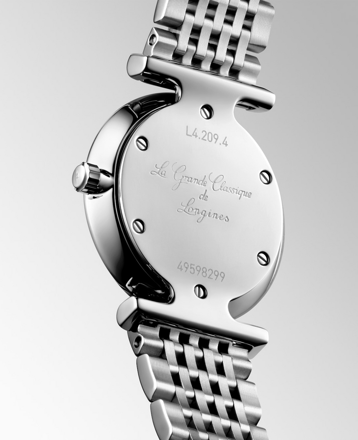 A Longines watch is displayed in the middle, angled to the right, showcasing the back of the dial on a white background. The back of the watch has La Grande Classique de Longines engraved in the middle of the dial.