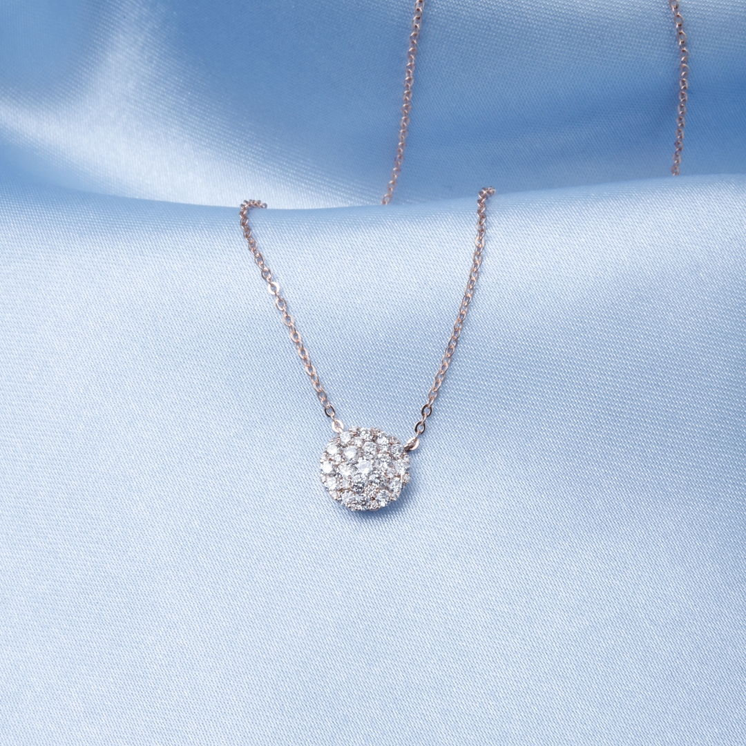 A close-up of a white-gold Cluster Round Diamond Necklace against a blue background. The necklace features round diamond-encrusted clusters.