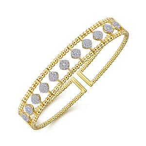 A yellow-gold bangle bracelet with a cuff design featuring beads around the edge and diamonds in the center is angled in the middle of a white background.