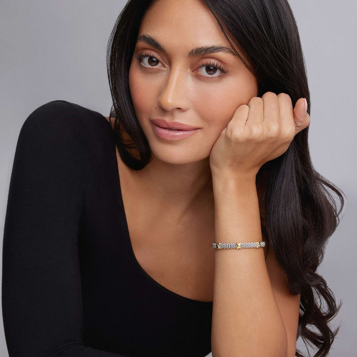 A woman is wearing a sterling silver bracelet featuring Caviar beading accented by three 18k gold x stations