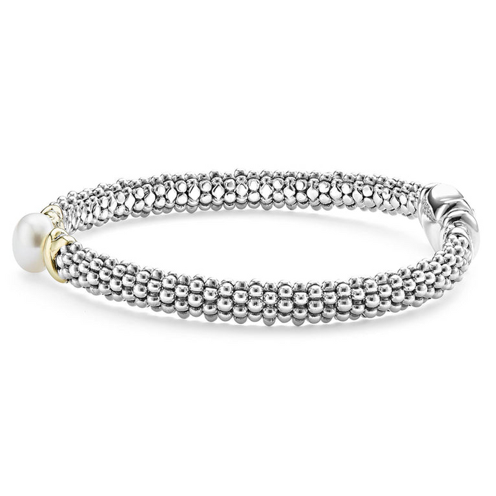 A side-view of a sterling silver bracelet in the middle of a white background featuring a freshwater cultured pearl framed by two 18K gold x stations