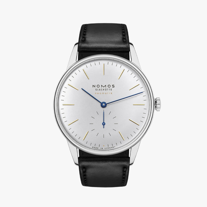 A Nomos Glashutte watch stands straight against a white background. It features a white dial, gold & blue hands and markers, a stainless steel bezel, and a black strap.