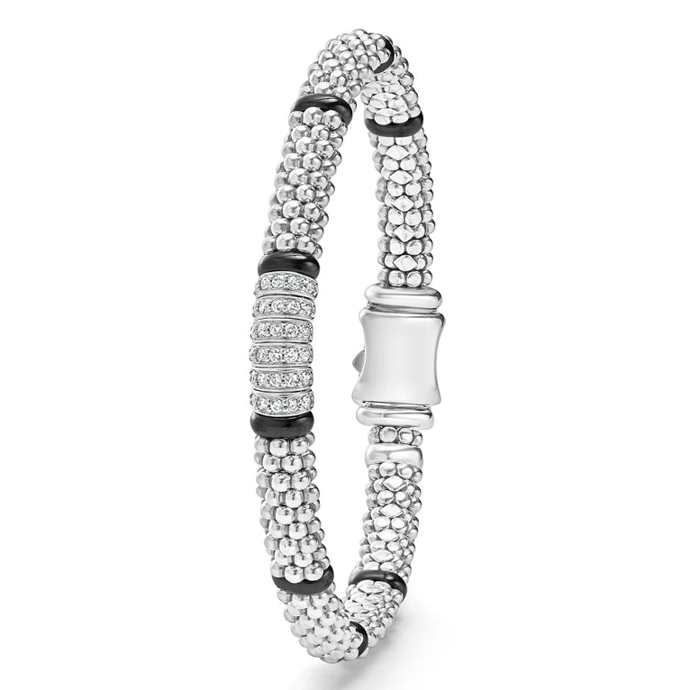 A sterling silver bracelet in the middle vertically of a white background features smooth black stations, diamond-set stations, and ceramic caviar beading.