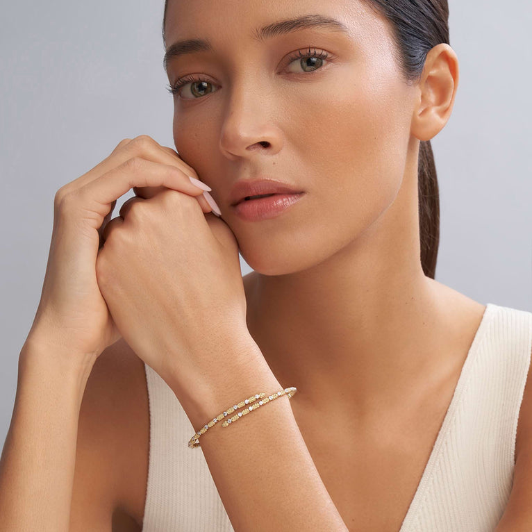 A woman wearing an 18K gold cuff bracelet featuring caviar beading and diamonds