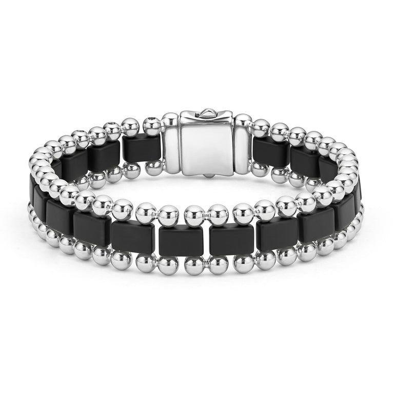 A stainless steel bracelet in the middle of a white background featuring matte black ceramic and caviar beading.