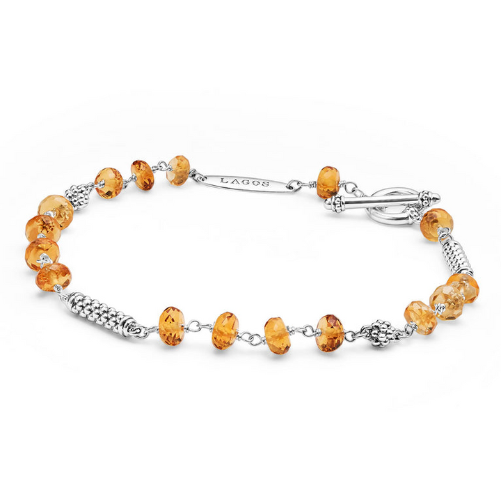 A sterling silver bracelet is displayed, angled in the middle of a white background, featuring citrine ceramic and silver Caviar beads.