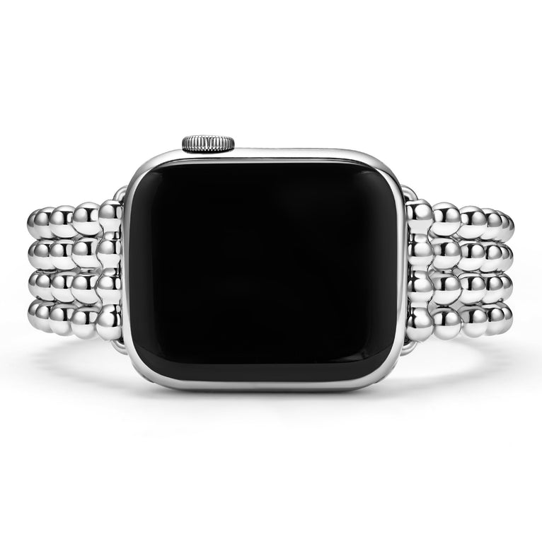 A close-up of a woman wearing an Apple Watch around her wrist. The watch band features four rows of stainless steel beading.