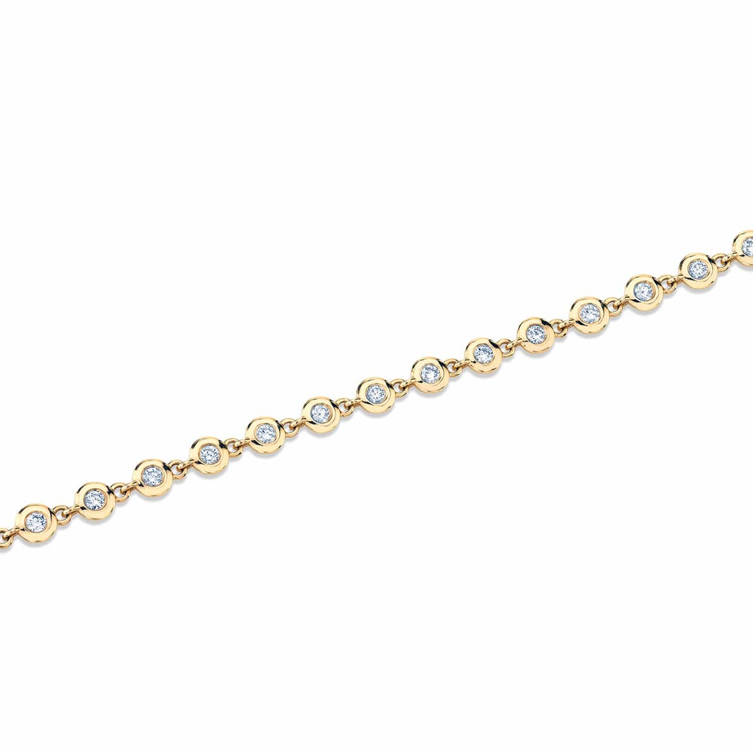 A yellow-gold bracelet lying flat across a white background. The bracelet features a row of bezel-set stones.