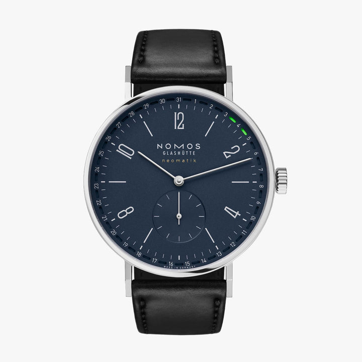 A Nomos Glashutte watch stands straight against a white background. It features a blue dial, silver hands and markers, a stainless steel bezel, and a black leather strap.