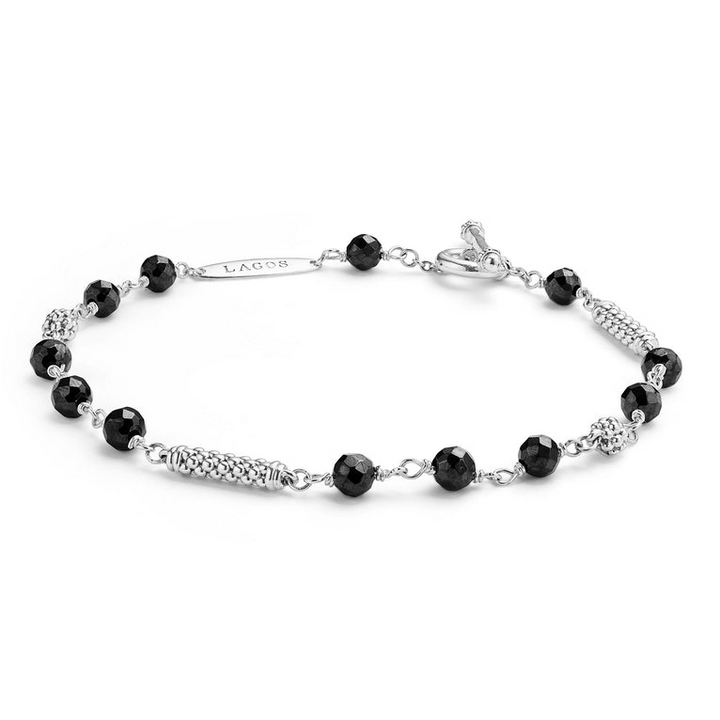 A sterling silver bracelet displayed angled in the middle of a white background featuring Black ceramic and silver Caviar beads.