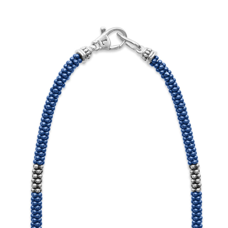 A sterling silver and ceramic beaded necklace in the middle of a white background featuring blue ceramic and silver caviar beading highlights the lobster clasp.