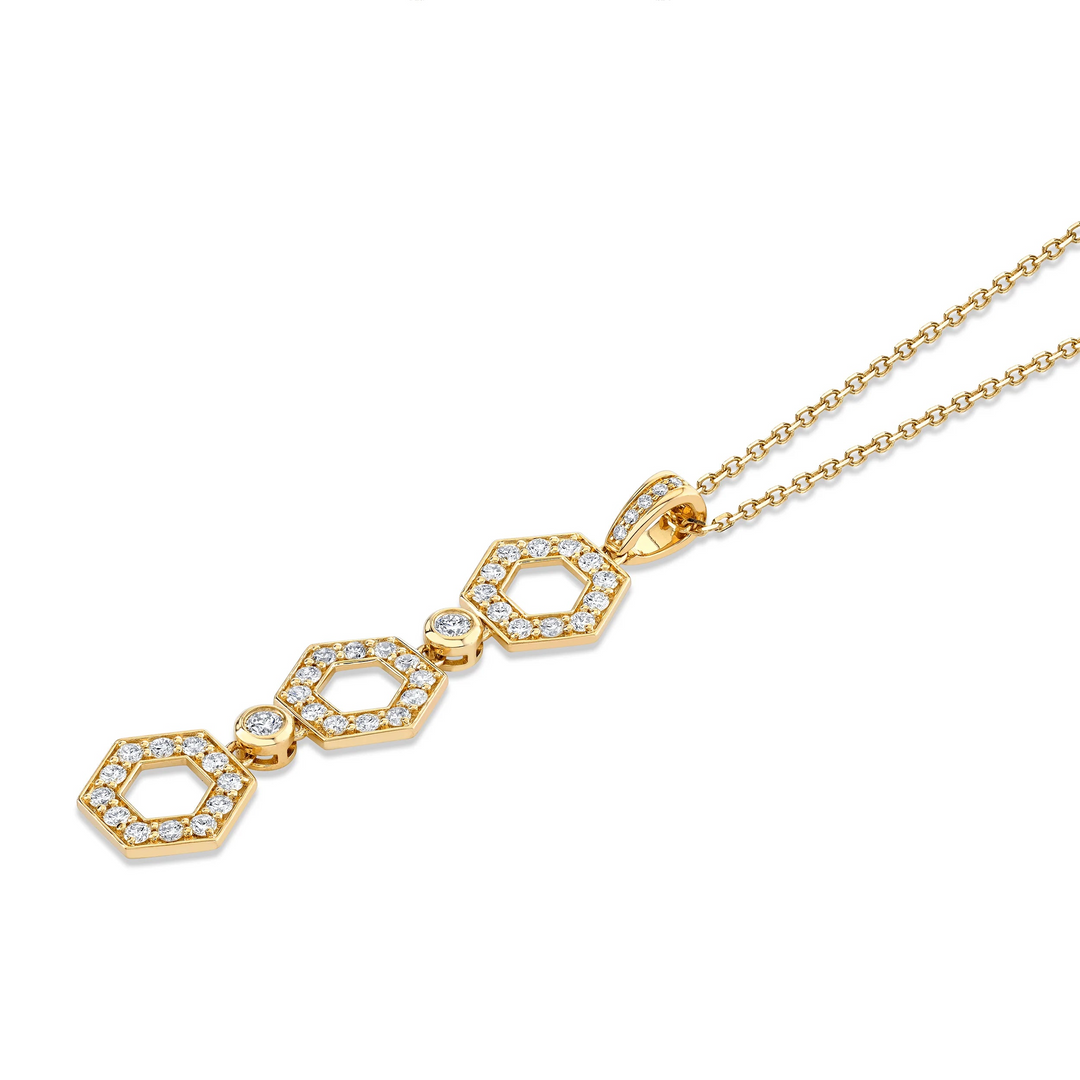 A yellow-gold necklace lying flat across a white background. The necklace features three hexagon motif pendants with round bezel-set diamonds.