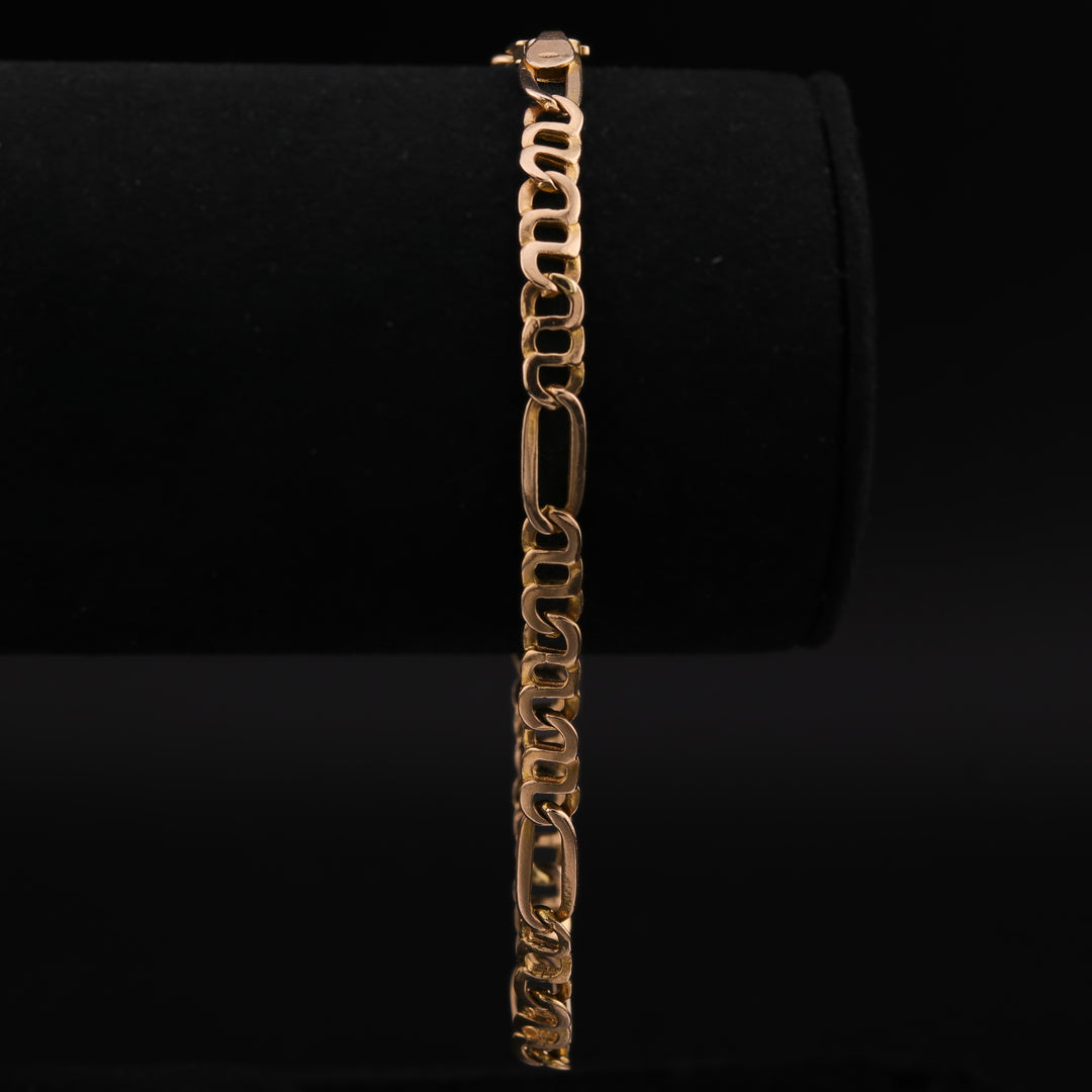 A close-up of a yellow-gold chain featuring a distinctive pattern of flattened links, with alternating smaller and larger links against a black background.