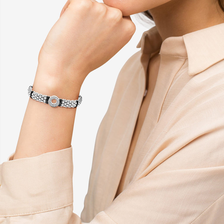 A woman wearing a sterling silver bracelet featuring smooth black ceramic and diamonds in a circle motif with Caviar beading 