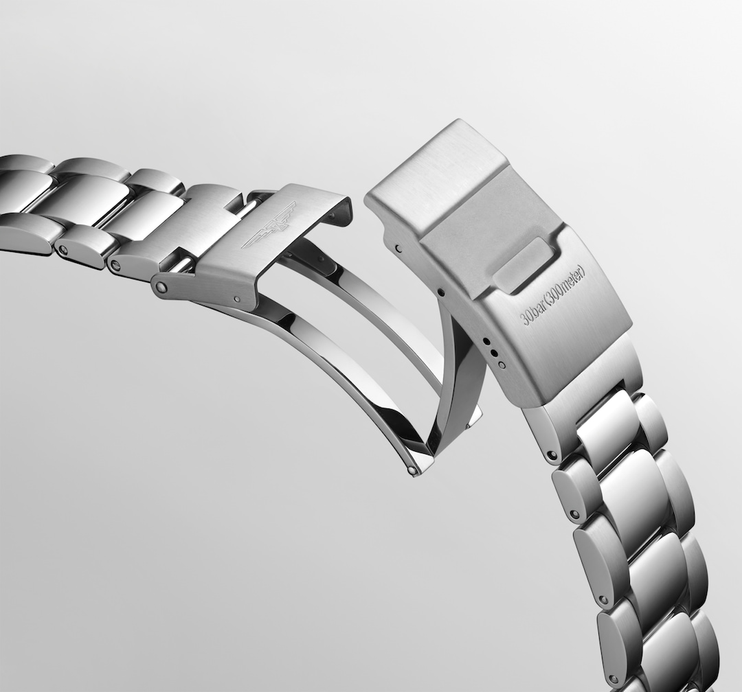 A close-up of a Longines watch angled showing the stainless steel bracelet and undone clasp. The Longines logo is on the top of the clasp.