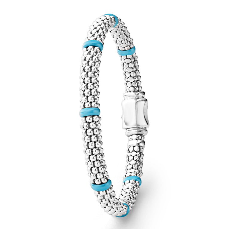 A Sterling Silver & 18K Gold bracelet standing vertically in the middle of a white background, featuring seven sterling silver stations and blue caviar beading