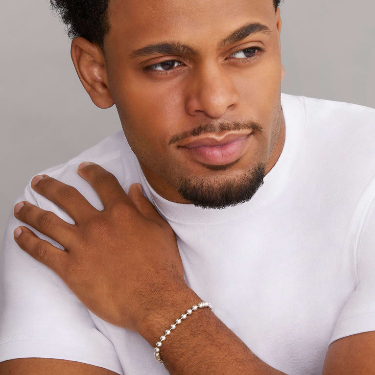 A man is wearing a sterling silver bracelet with Smooth sterling silver accented by Caviar beaded stations on a ball chain.