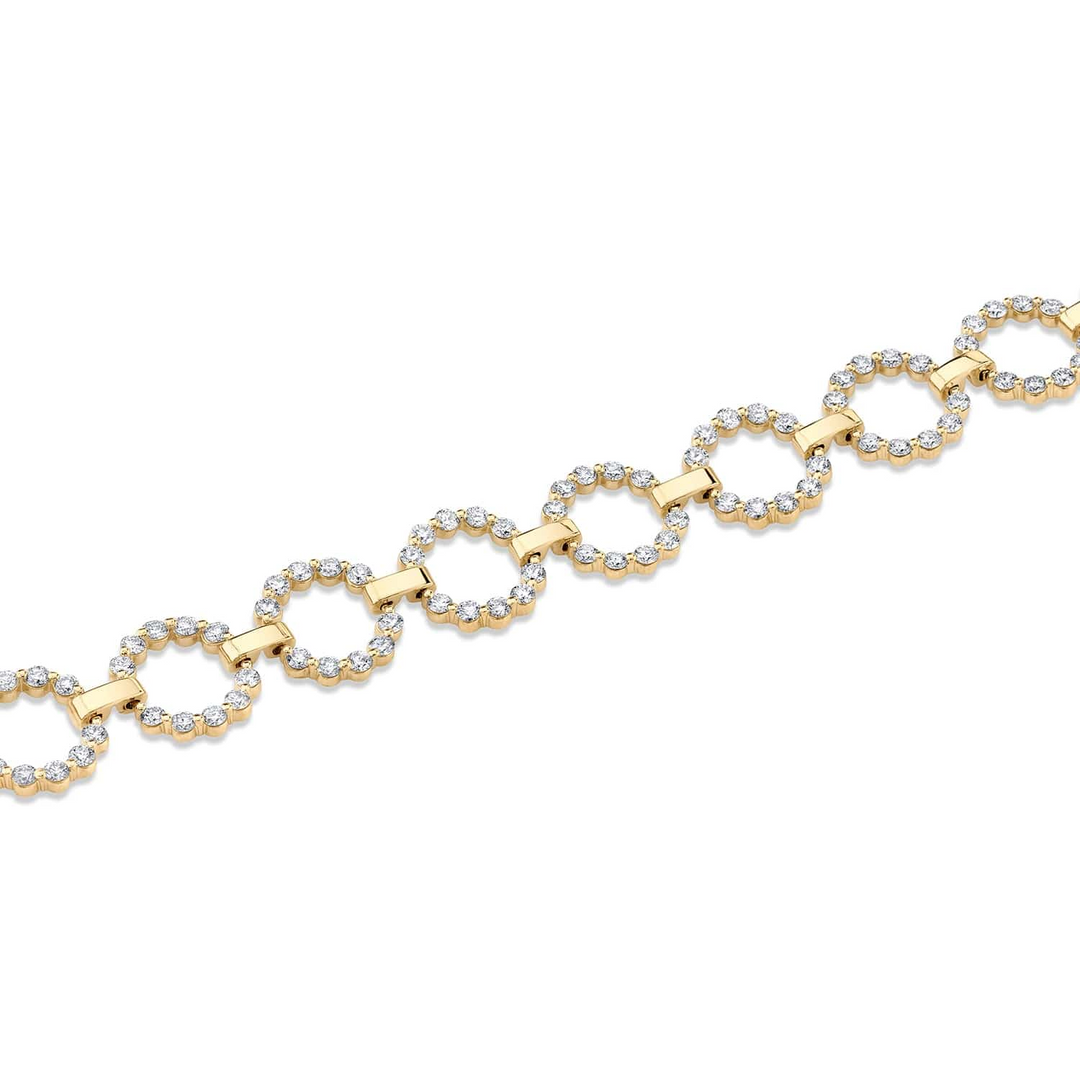 A yellow-gold bracelet lying flat across a white background. The bracelet features a row of bezel-set round stones with circle links.