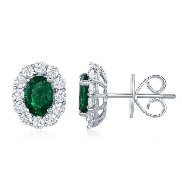 A pair of stud earrings displayed in the middle of a white background, the right earring angled to the side. The earring features an oval emerald center stone with surrounding diamonds.