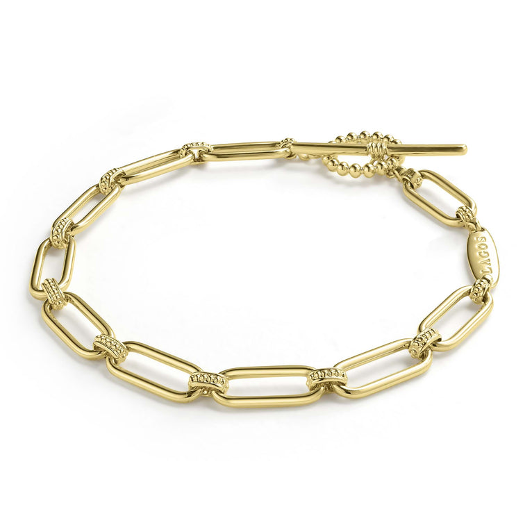 An 18K gold link bracelet angled laying in the middle with a white background, featuring caviar beading and fluting elements 