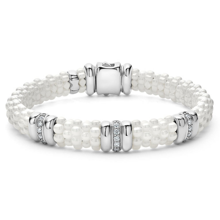 A sterling silver bracelet in the middle of a white background featuring three diamond stations, white ceramic caviar beading, and sterling silver stations