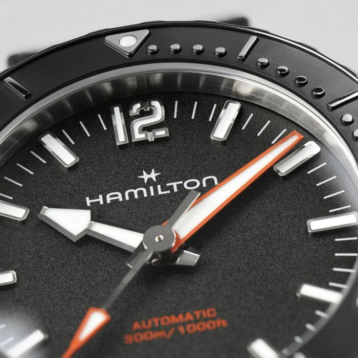 A close-up of a Hamilton watch, focusing on the black dial and black bezel.