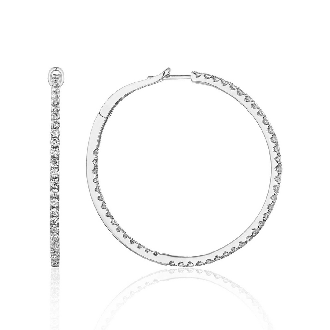 A pair of hoop earrings with a single row of round diamonds. The right earring is angled to the side.