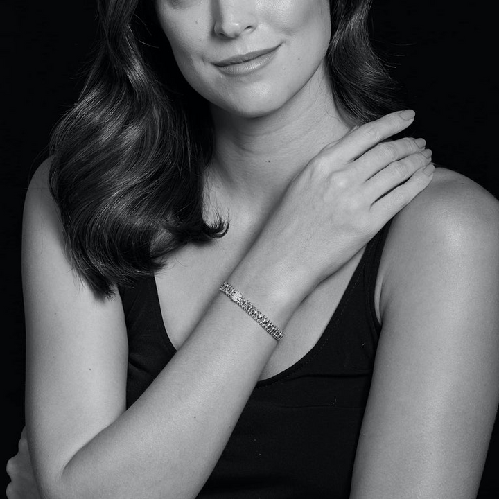 A woman wearing a sterling silver link bracelet featuring single pavé diamond station framed by sterling silver Caviar beading