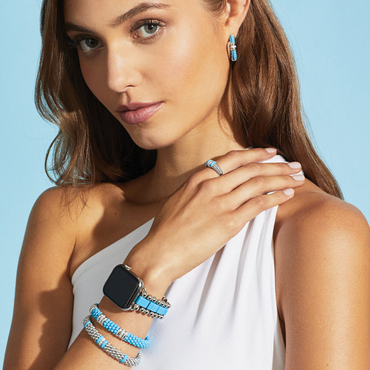 A woman wearing a sterling silver bracelet, featuring three diamond stations, blue ceramic caviar beading, and sterling silver stations