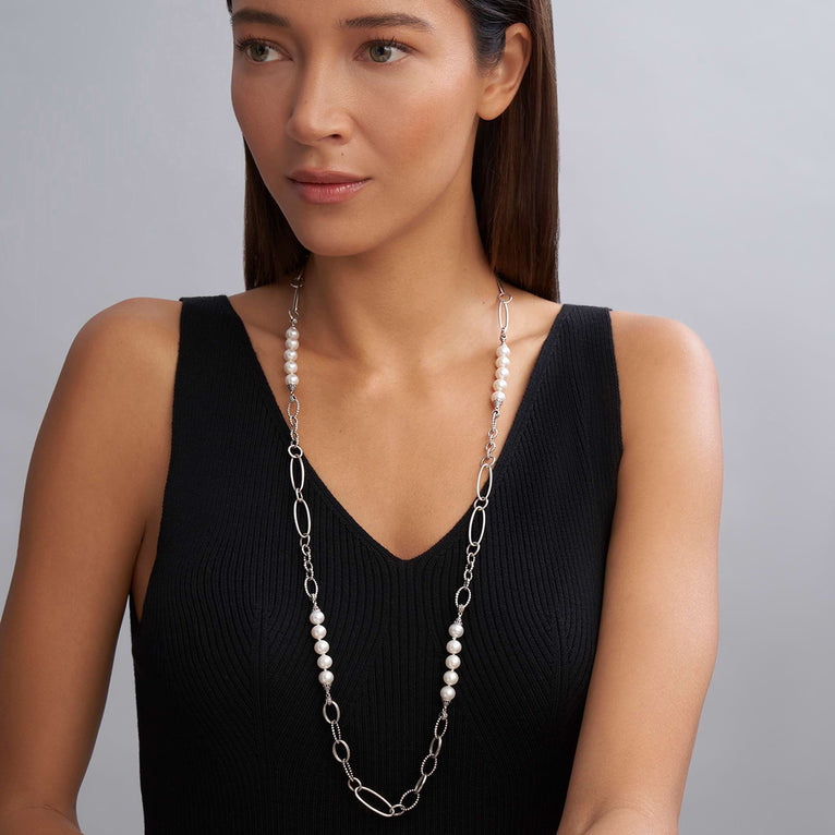 A close-up of a woman wearing a sterling silver necklace featuring five cultured freshwater pearl stations and caviar beading against a white background.