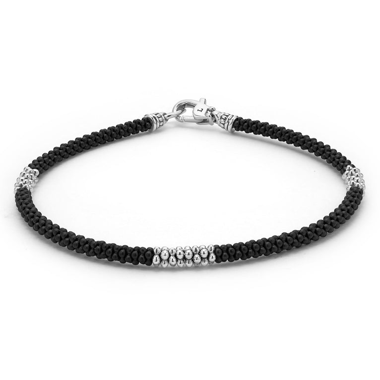 A bracelet angled in the middle of a white background featuring three sterling silver stations and Matte black ceramic caviar beading