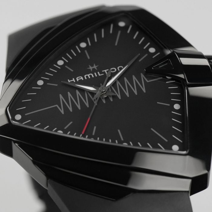 A close-up of a Hamilton triangular-shaped watch, focusing on the black dial and black bezel.