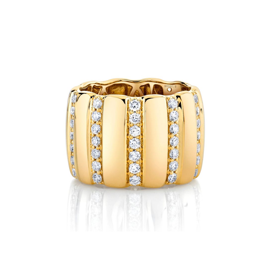 A yellow-gold ring lying flat across a white background. The ring features a wide cigar band with rows of pave-set round diamonds.