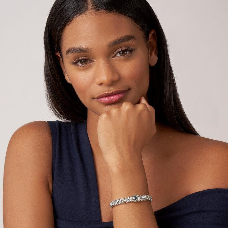 A woman wearing a Sterling silver and 18k gold bracelet featuring a Swiss blue topaz gemstone and sterling silver Caviar beading with 18K gold detailing.