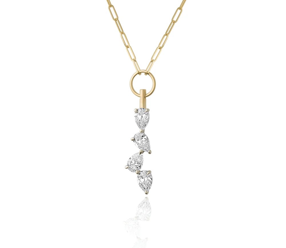Close up of a yellow gold chain necklace with three pear shaped diamonds dangling from a gold hooop on a white background.