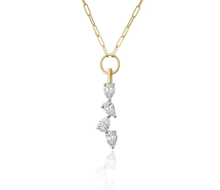 Close up of a yellow gold chain necklace with three pear shaped diamonds dangling from a gold hooop on a white background.