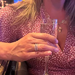 Person holding a glass with a close-up of a ring on a blurred background