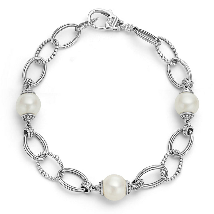 A Sterling Silver link bracelet rests in the middle of a white background. It has three cultured freshwater pearl stations and caviar-beaded links.